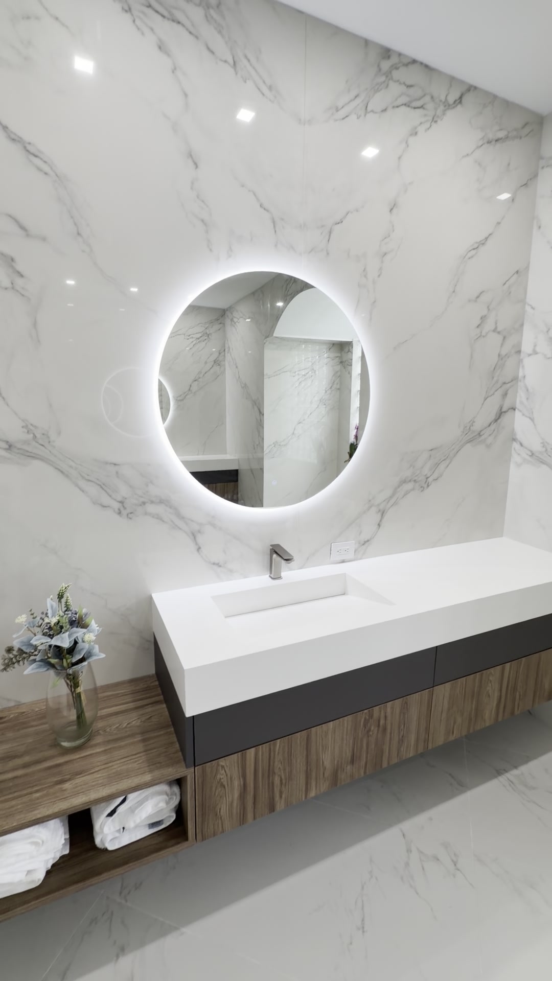 Illuminated circular mirror above a marble vanity